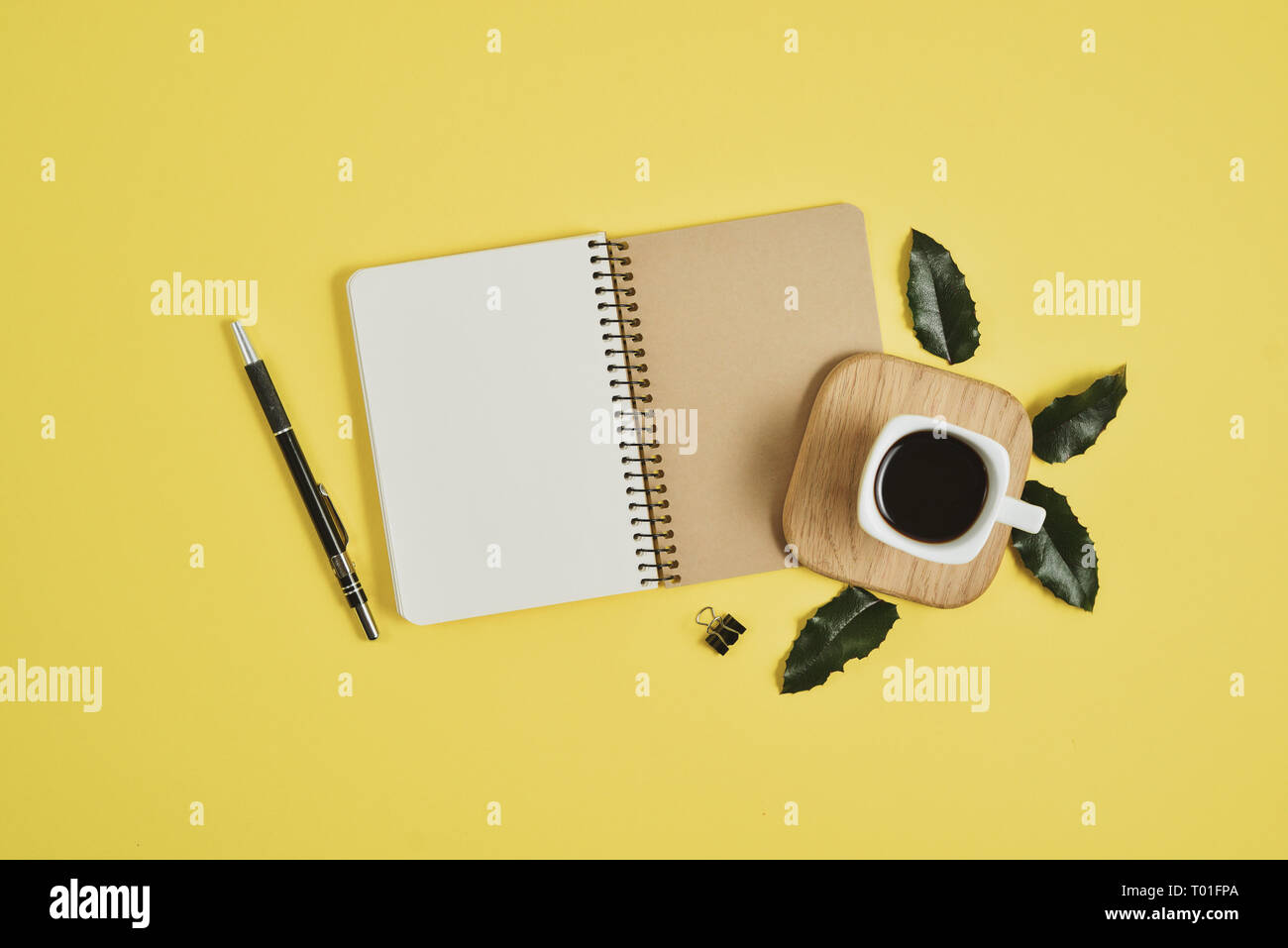 Gelb Büro Schreibtisch Tisch mit leeren Notebook, grünes Blatt, Stift, Zubehör und Kaffee Tasse. Flach, Ansicht von oben mit der Kopie. Stilvolle weibliche Konzept. Stockfoto