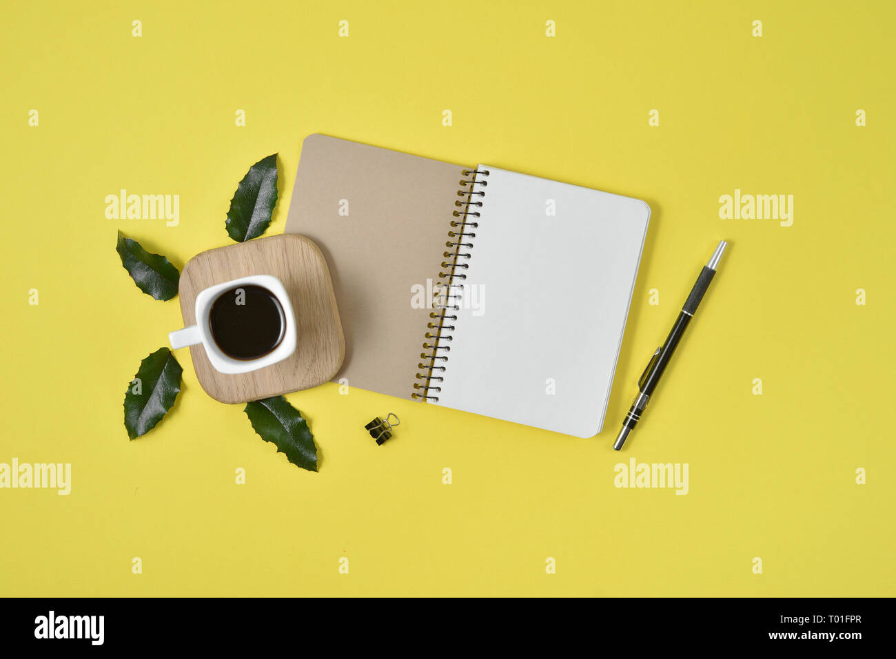 Gelb Büro Schreibtisch Tisch mit leeren Notebook, grünes Blatt, Stift, Zubehör und Kaffee Tasse. Flach, Ansicht von oben mit der Kopie. Stilvolle weibliche Konzept. Stockfoto