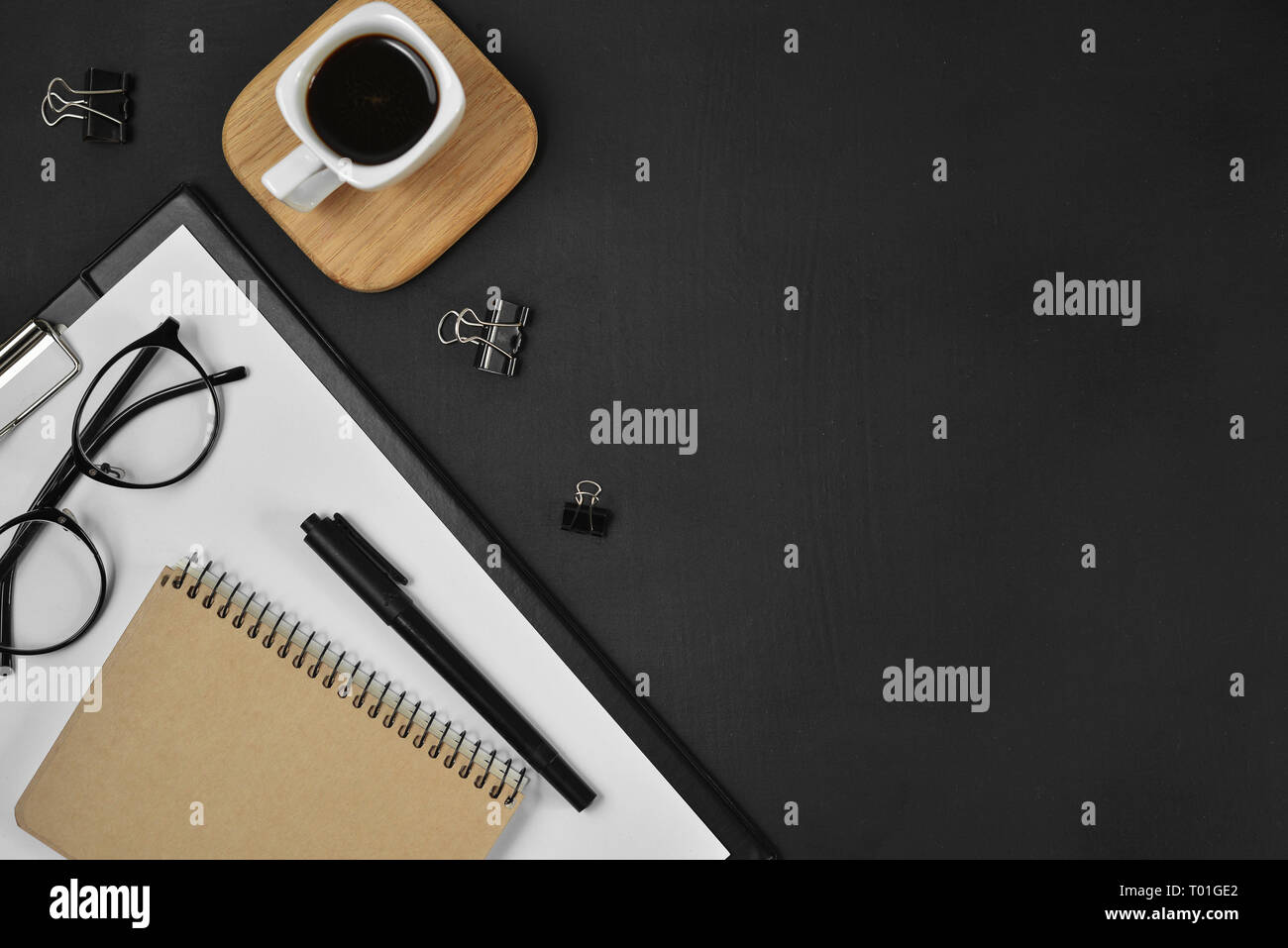 Mock up Arbeitsbereich mit leeren Clip Board, Bürobedarf, Stift, Kaffeetasse, Notepad und Brillen auf dunklem Hintergrund. Flach, Ansicht von oben, kopieren Raum Stockfoto