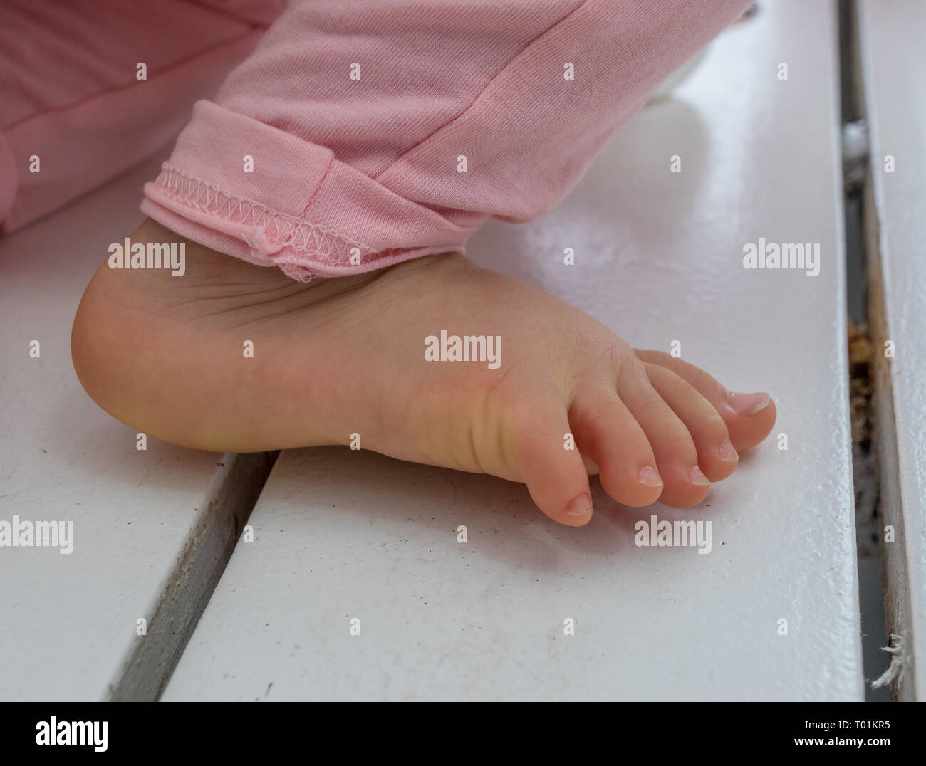 Den rechten Fuß von einem Baby isoliert Closeup auf einem weißen Holz- oberfläche Bild mit Kopie Raum im Querformat. Stockfoto
