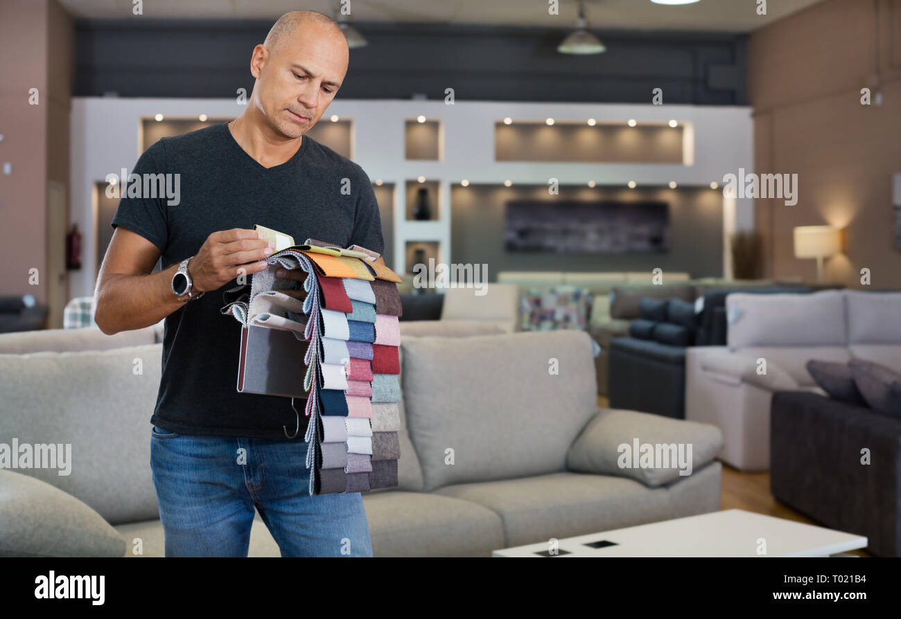 Männliche Kunden Auswahl Bezugsstoff aus Katalog mit Proben in einem Möbelgeschäft Stockfoto