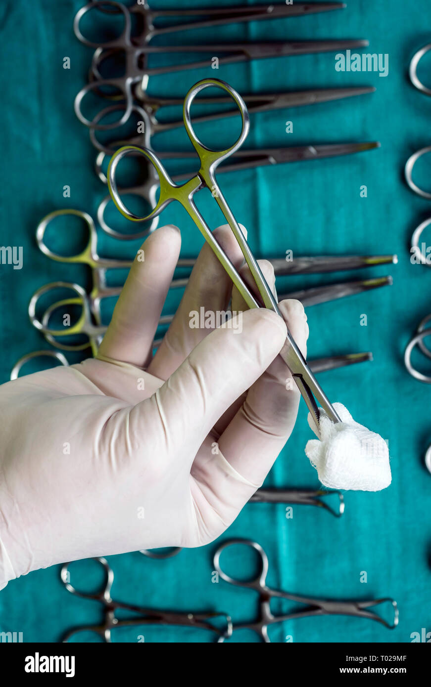 Chirurg im Operationssaal arbeiten, die Hände mit Handschuhen holding Schere mit torunda, konzeptionelle Bild, vertikale Zusammensetzung Stockfoto