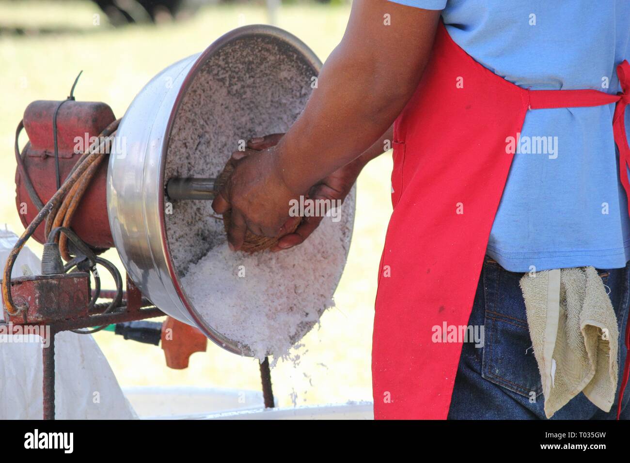 Eine nicht erkennbare Mann coconut Schaben mit einem Schaber Maschine im Freien Stockfoto