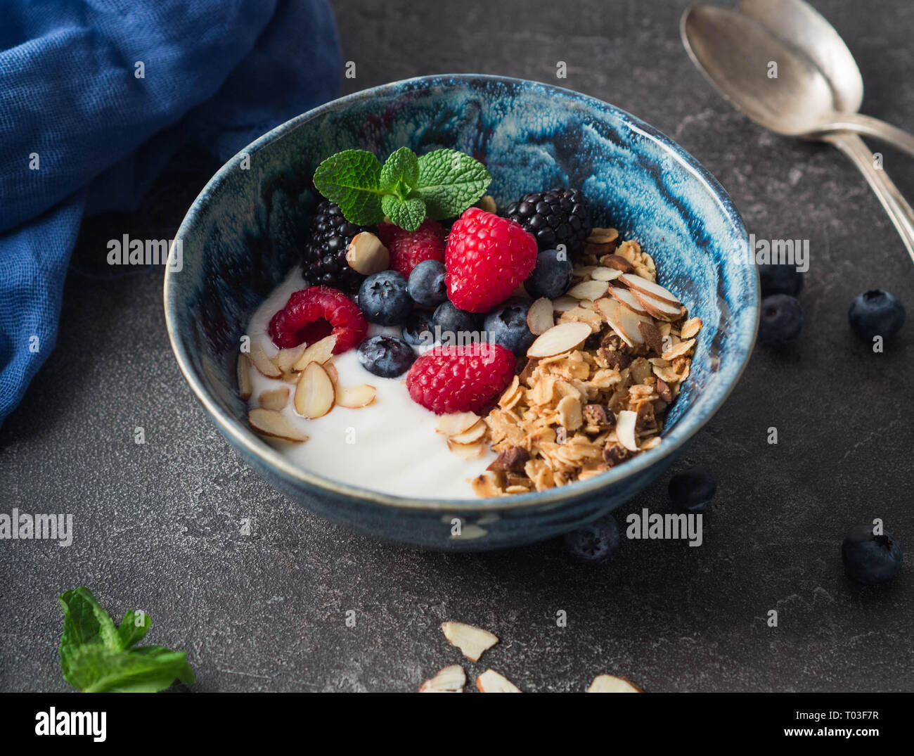 Eine Schüssel mit hausgemachtem Müsli, Joghurt, Mandel Blüten und frischen Beeren. vegetarisches Essen Konzept Stockfoto