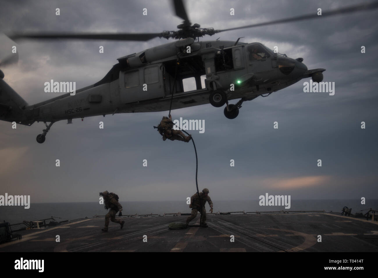 U.S. Coast Guard Maritime Sicherheit Reaktion Teammitglieder rappel auf das Flight Deck der geführten Anti-raketen-Zerstörer USS Chung-Hoon (DDG93) aus einem MH-60S Sea Hawk, Hubschrauber Meer Combat Squadron (HSC) 26, bei einem einfügevorgang Training übung im Arabischen Golf, 14. März 2019 zugeordnet. Die chung-hoon ist in die USA 5 Flotte Bereich der Maßnahmen zur Unterstützung der Marine im Einsatz für die Stabilität und Sicherheit in der Region zu gewährleisten und verbindet das Mittelmeer und den Pazifischen Raum durch den westlichen Indischen Ozean und drei strategischen Punkten ersticken. (U.S. Marine Foto von Masse Kommu Stockfoto