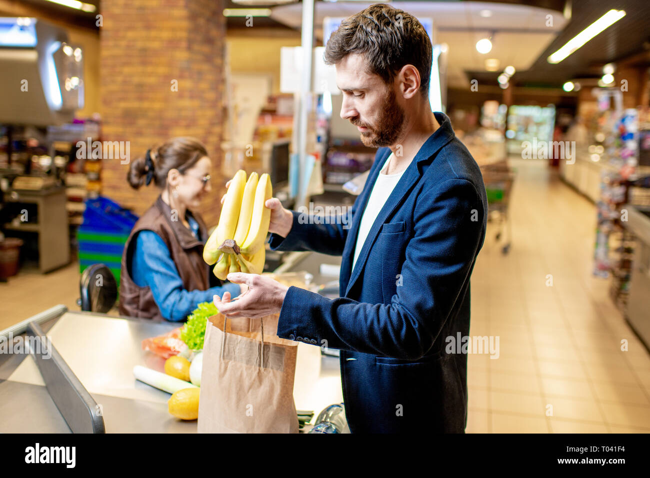 Geschäftsmann kaufen gesunde Lebensmittel, Verpackung Produkte an der Kasse mit fröhlichen Kassierer im Supermarkt Stockfoto