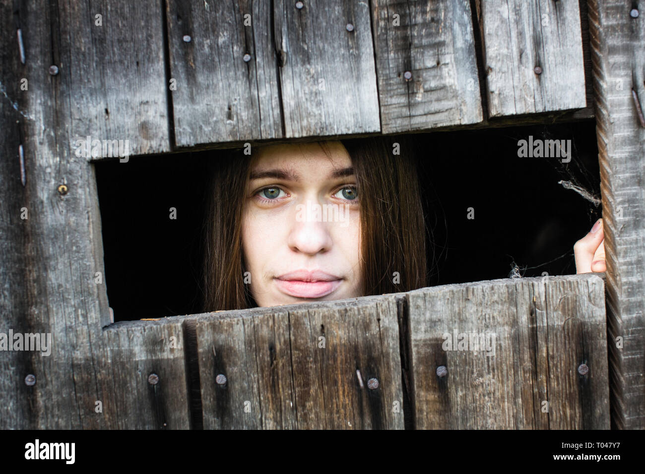 Frau mit langen Haaren und schönen Lippen, schaut aus dem holzschuppen ...
