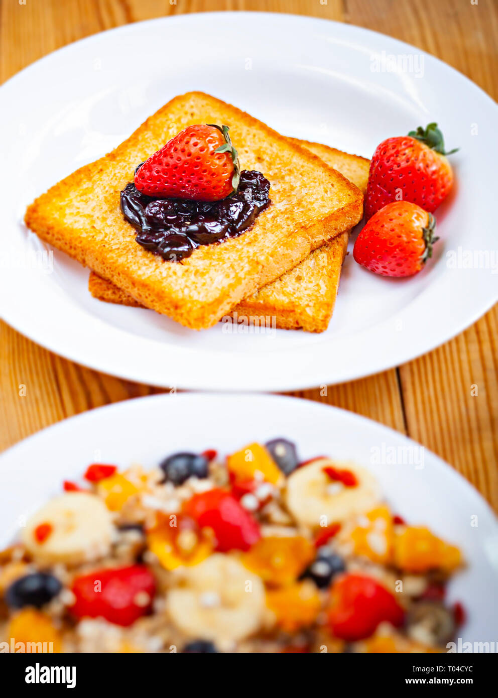 Tabelle Bild oben Brot Toast mit dem Belag der Cranberry Konfitüre, Erdbeere und gesunde Mischung Früchte Haferflocken in Weiß Platte am Esstisch aus Holz. Stockfoto