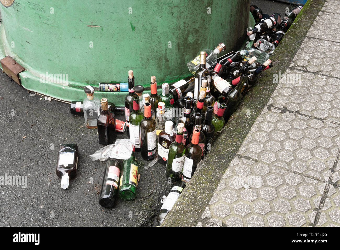 Galizien, Spanien; 8. März 2019: Viele leere Glasflaschen in der Nähe von einem Glasbehälter. Recycling Konzept Stockfoto