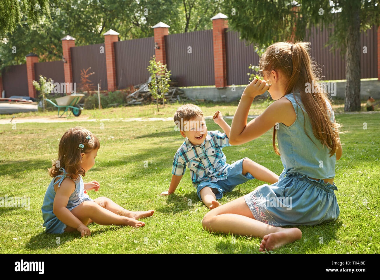 Fröhlich verspielten Kinder im Freien im Sommer auf Gras in einem Hinterhof Stockfoto