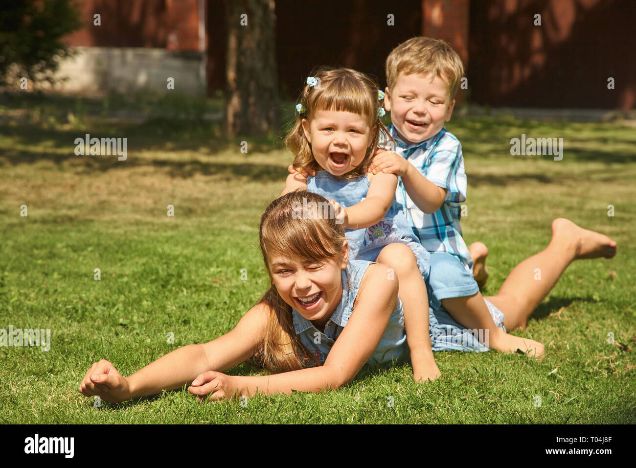 Fröhlich verspielten Kinder im Freien im Sommer auf Gras in einem Hinterhof Stockfoto