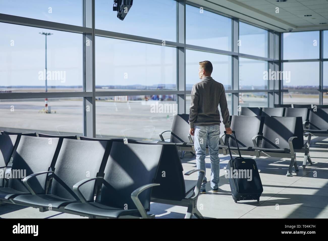 Reisende im Flughafen Terminal. Junger Mann mit Gepäck warten auf Flugzeug. Stockfoto