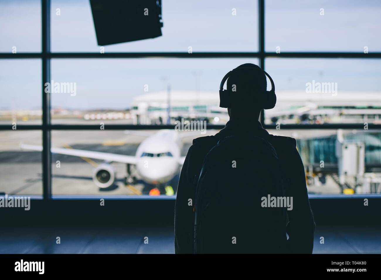 Passagier mit Kopfhörern. Junger Mann zu Fuß durch Flughafen Flugzeug. Stockfoto