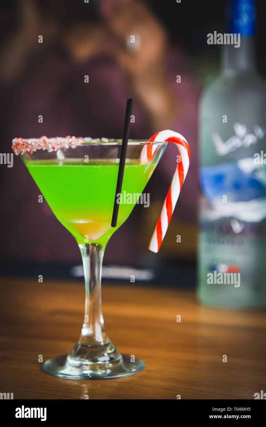 Weihnachten Cocktail mit Zuckerstange garnieren und Flasche Wodka im Hintergrund Stockfoto