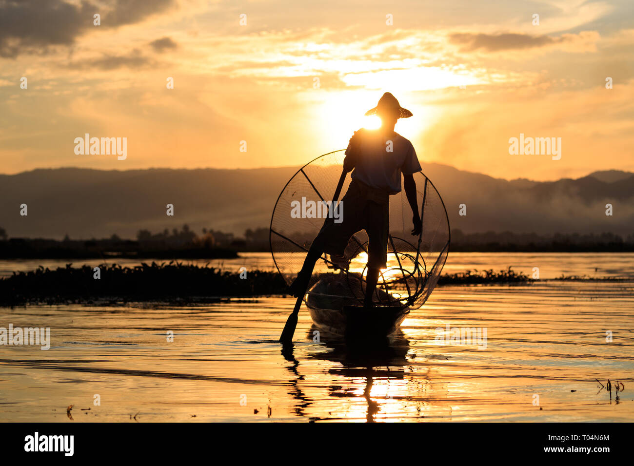 Die Fischer fischen mit großen Netz in traditionellen und einzigartigen 1-Bein rudern Stil während der Sonnenuntergang am Inle See im Shan Staat, Myanmar, Birma Stockfoto