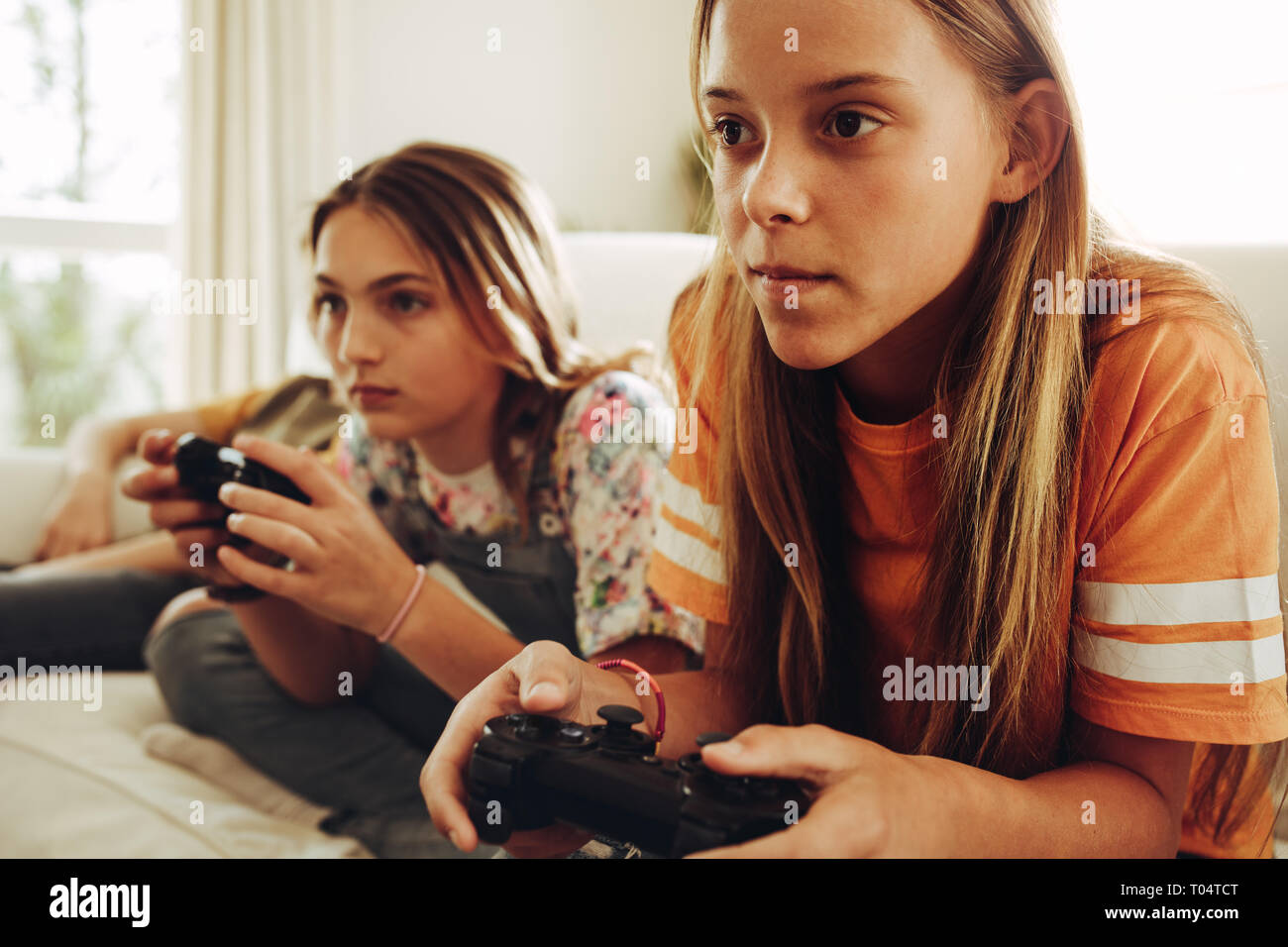 Nahaufnahme von zwei Jugendmädchen spielen video game Holding Joysticks. Mädchen auf der Couch zu Hause sitzen und spielen video game mit großem Interesse. Stockfoto