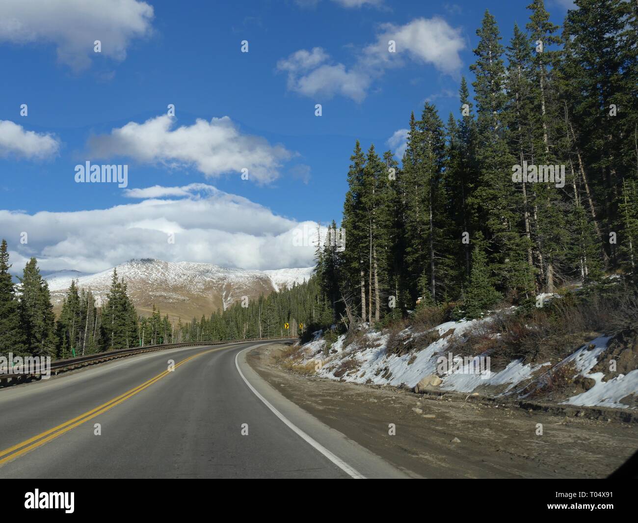 Einsame malerische Straße von hohen grünen Bäumen gesäumt mit Schnee bedeckten Berge in die Colorado Rockies, Stockfoto