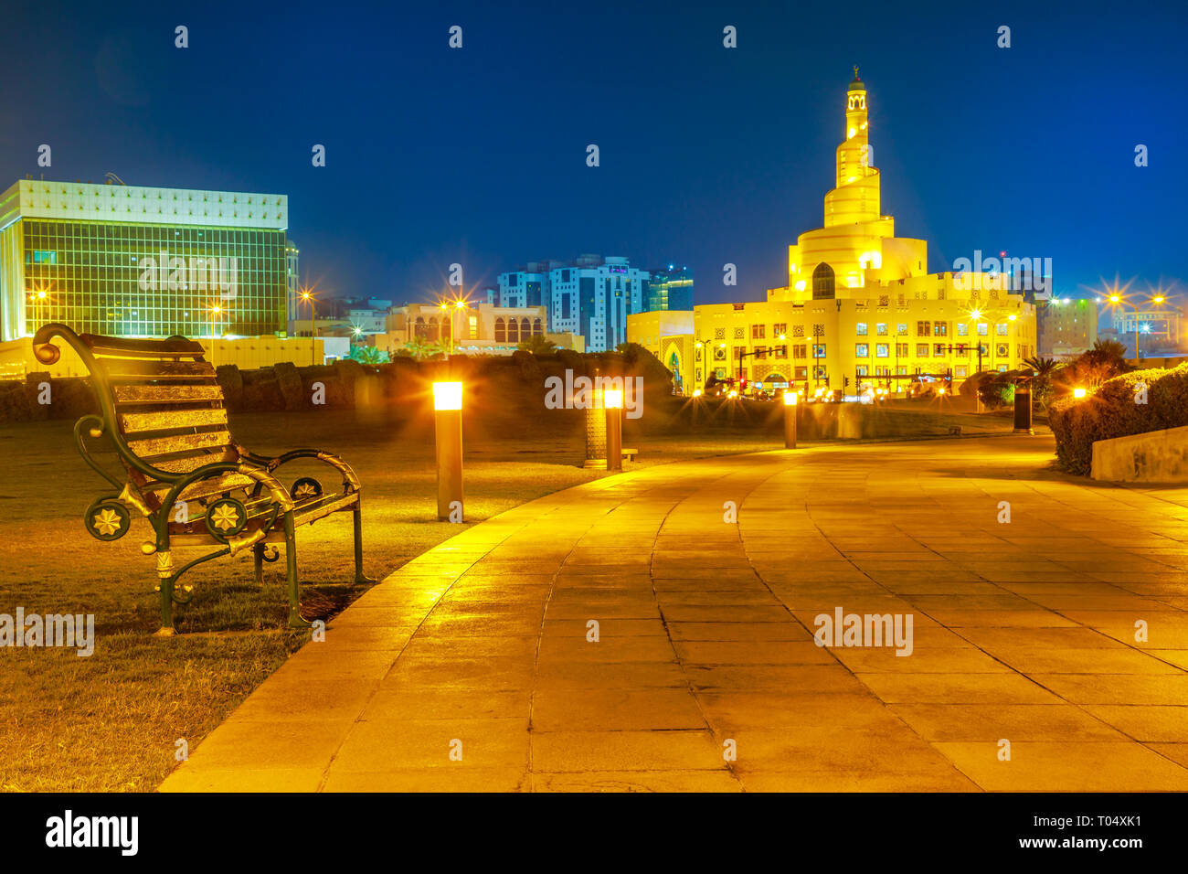 Sitzbank und Gehweg in Souq Waqif Garten in der Nähe von Doha Corniche mit Doha Moschee auf dem Hintergrund. Doha in Katar, Naher Osten, Arabische Halbinsel in Stockfoto