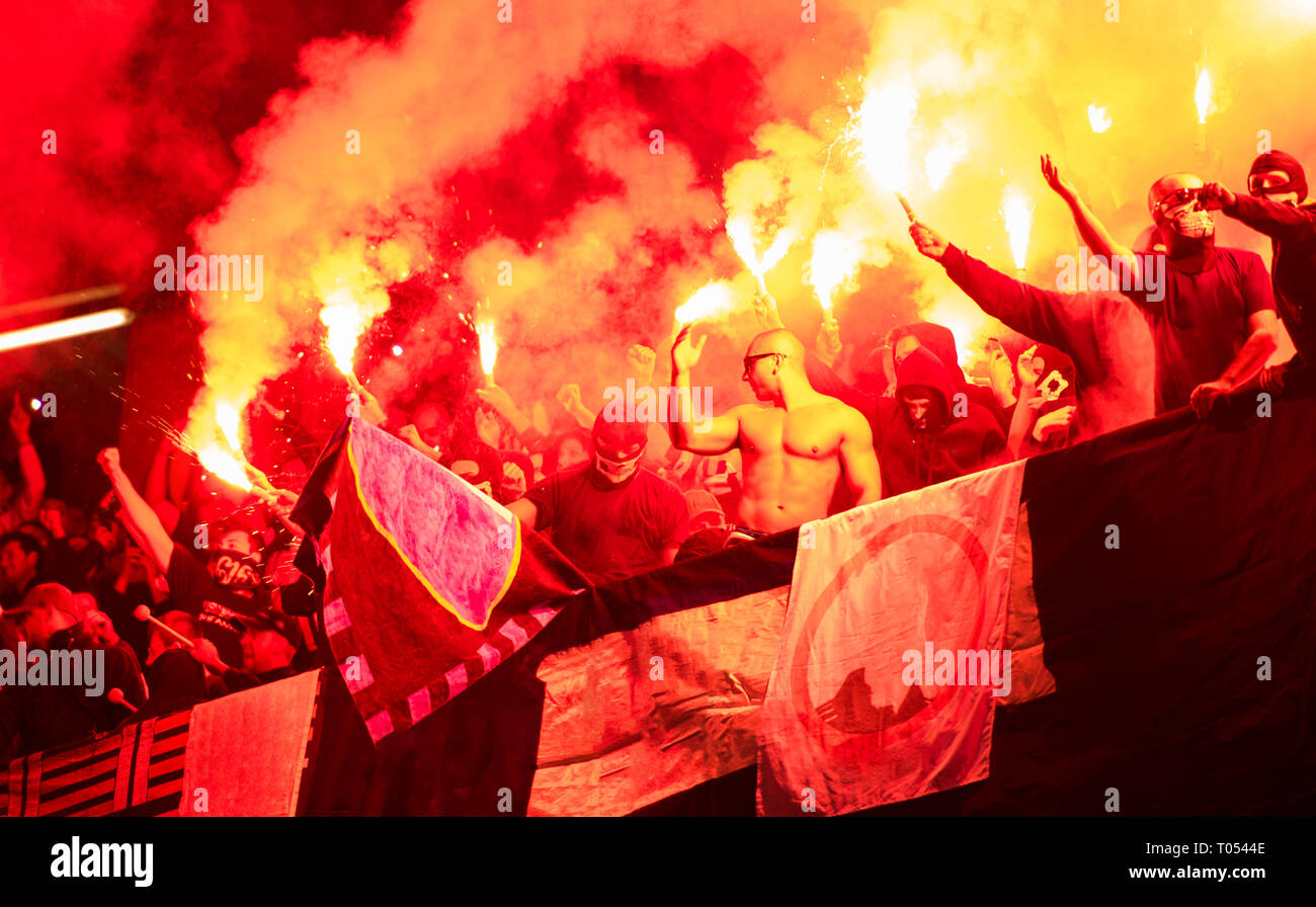 Fußball-Hooligans mit Maske halten Fackeln in Feuer, während Ihre Lieblingsmannschaft Unterstützung bei einem Spiel im Stadion Stockfoto