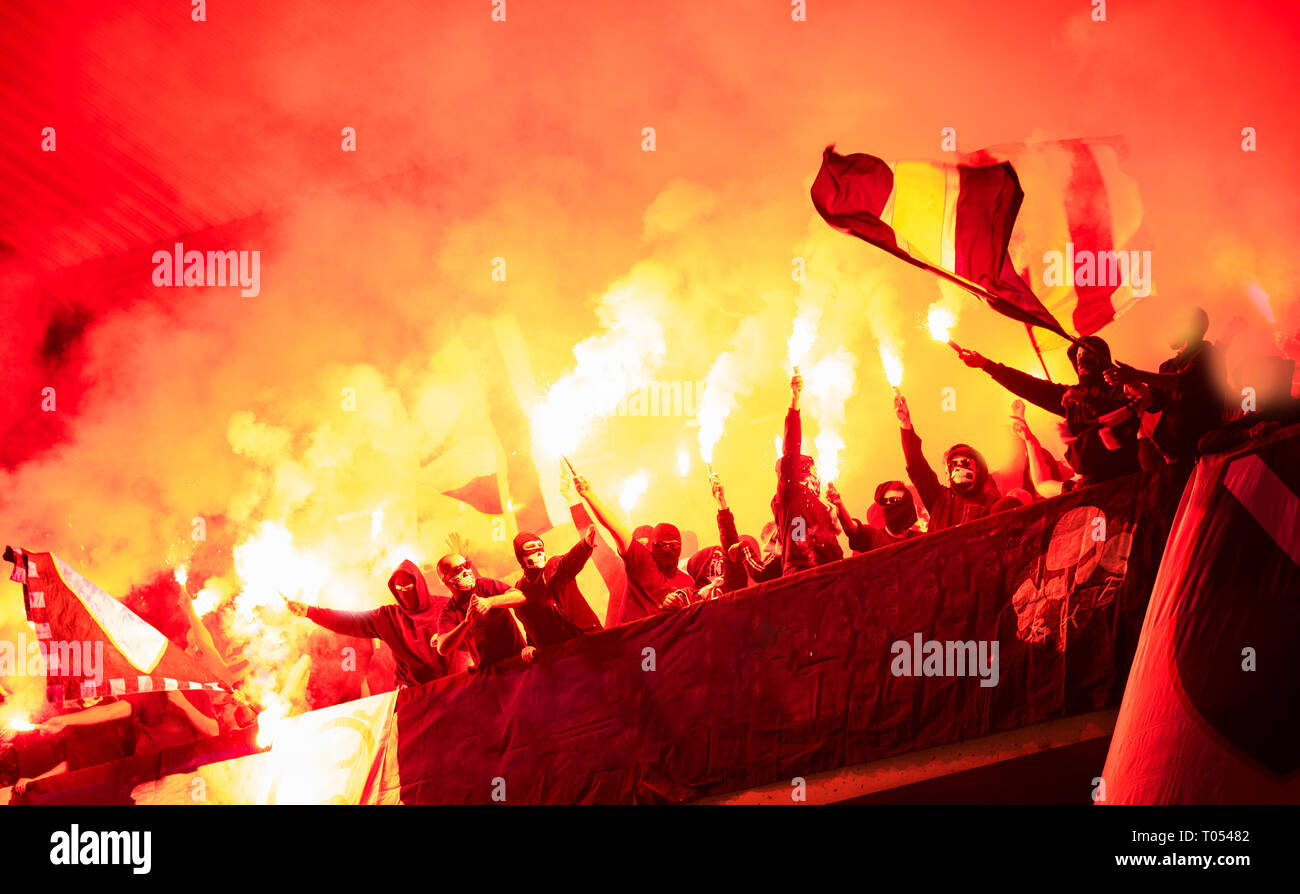 Fußball-Hooligans mit Maske halten Fackeln in Feuer, während Ihre Lieblingsmannschaft Unterstützung bei einem Spiel im Stadion Stockfoto