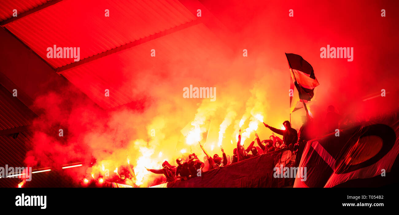 Fußball-Hooligans mit Maske halten Fackeln in Feuer, während Ihre Lieblingsmannschaft Unterstützung bei einem Spiel im Stadion Stockfoto