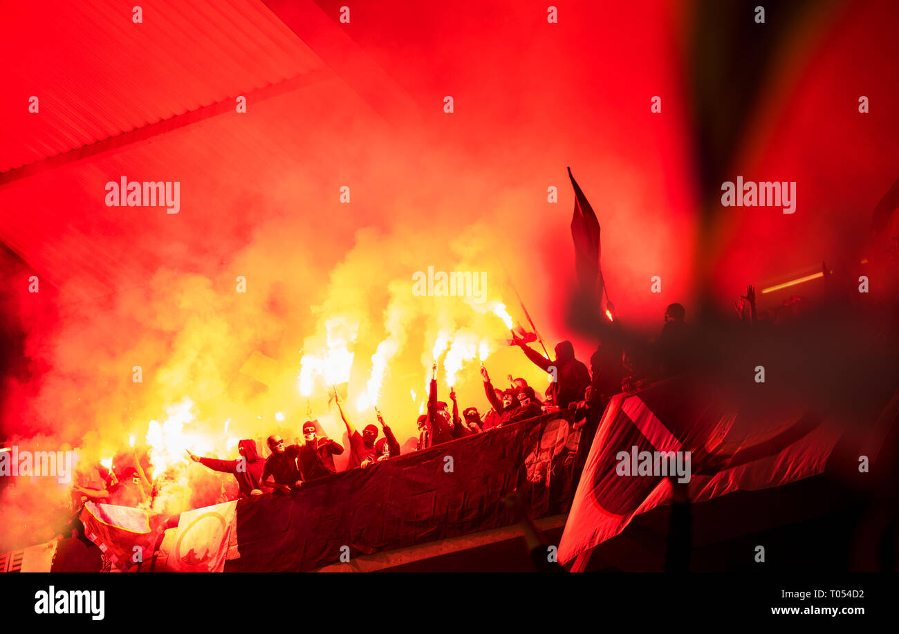 Fußball-Hooligans mit Maske halten Fackeln in Feuer, während Ihre Lieblingsmannschaft Unterstützung bei einem Spiel im Stadion Stockfoto