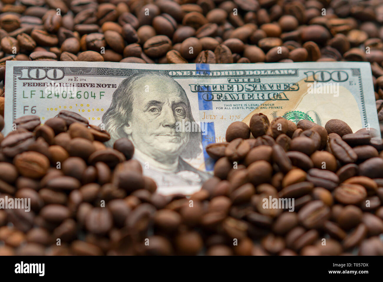 Banknote von 100 US-Dollar, zwischen Körner von Kaffee. Business Konzept für den Kauf, den Verkauf, die Lieferung und den Vertrieb von Kaffee. Stockfoto Banknote von 100 US-Dollar, zwischen Körner von Kaffee. Business Konzept für den Kauf, den Verkauf, die Lieferung und den Vertrieb von Kaffee. Stockfoto