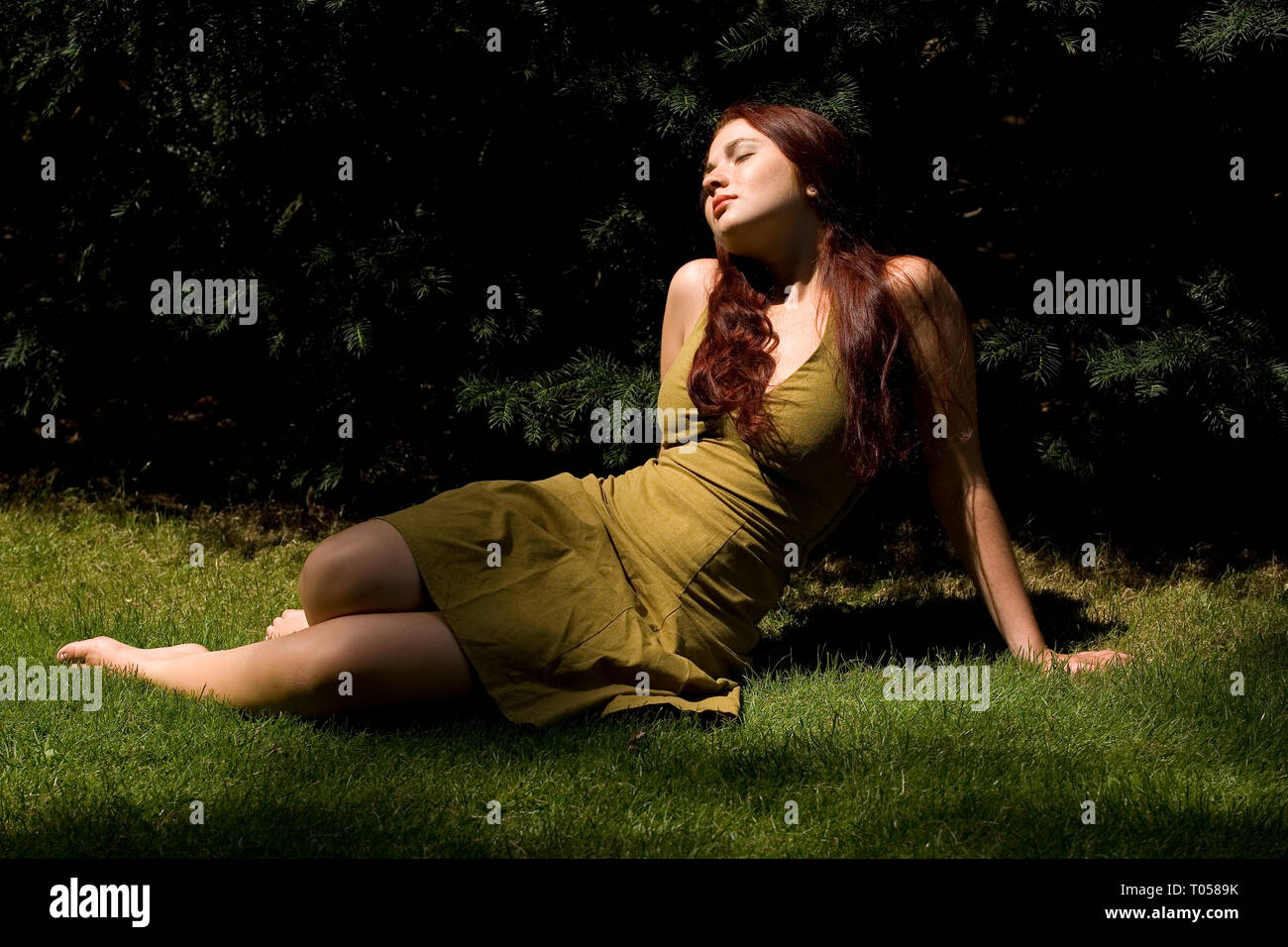Eine junge Frau liegt entspannt in der Wiese und geniesst die Sonne Stockfoto
