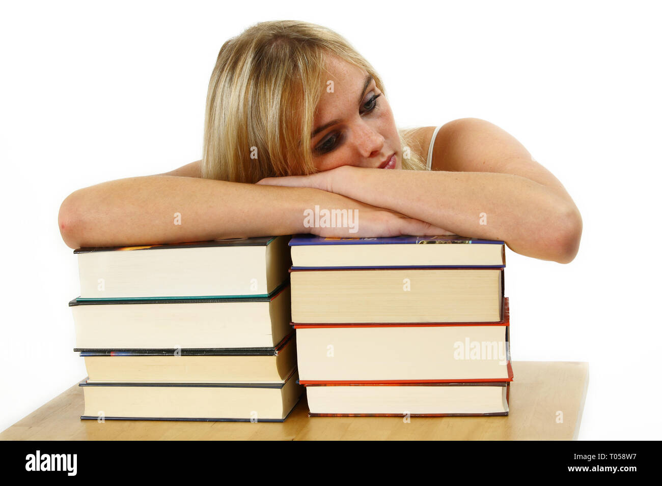 Eine junge Frau lehnt sich auf einem Stapel Bücher erschöpft. Gegen einen weißen Hintergrund. Stockfoto