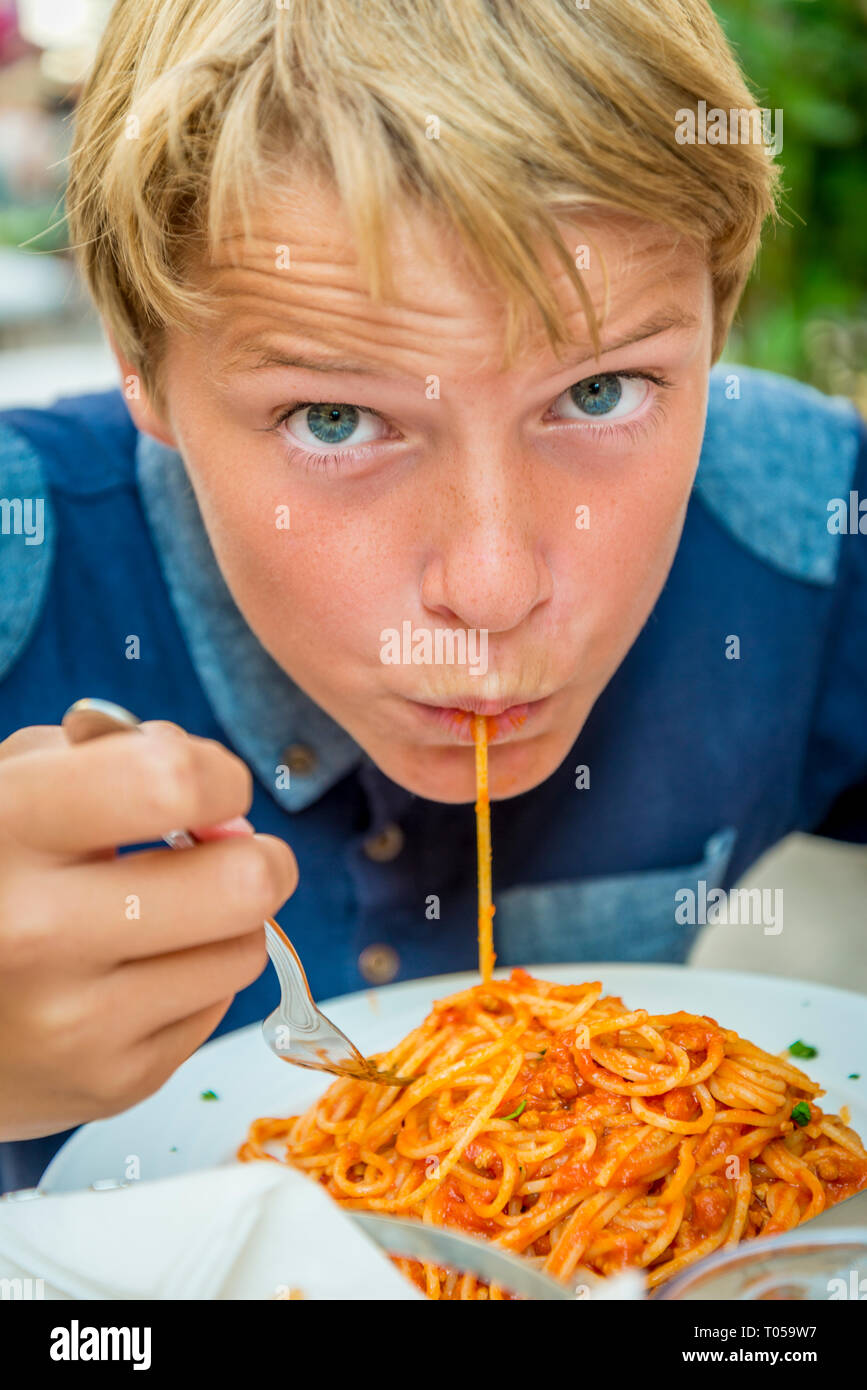 Blonde Junge mit blauen Augen essen Spaghetti Stockfoto