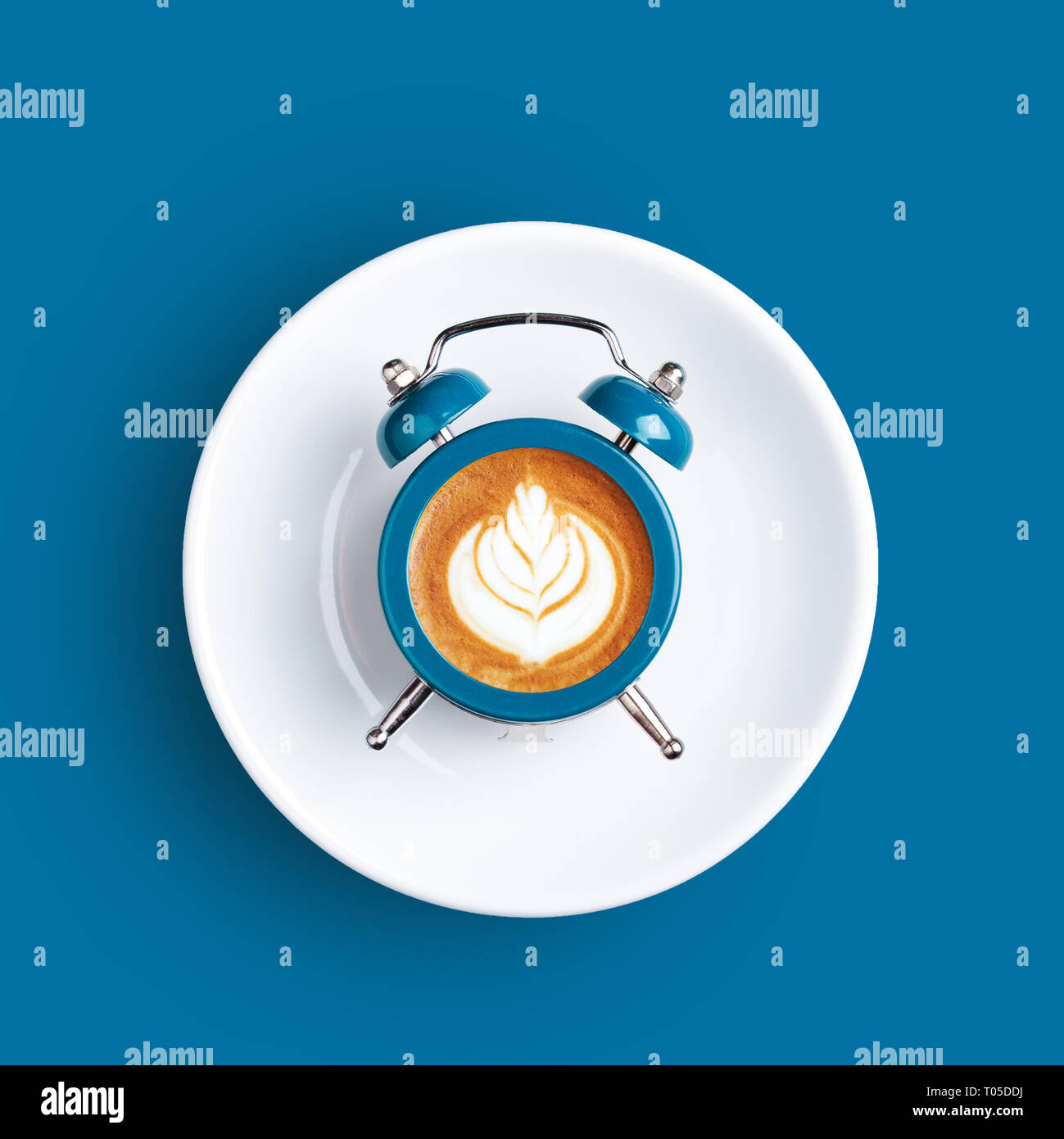 Wecker mit dem Zifferblatt mit Cappuccino auf blauem Hintergrund. Minimale gestylt kaffee zeit Konzept. Stockfoto