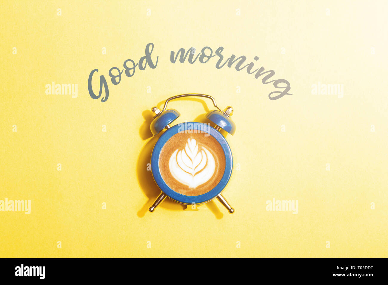 Wecker mit dem Zifferblatt mit Cappuccino auf gelben Hintergrund. Minimale gestylt kaffee zeit Konzept mit Aufschrift Guten Morgen. Stockfoto