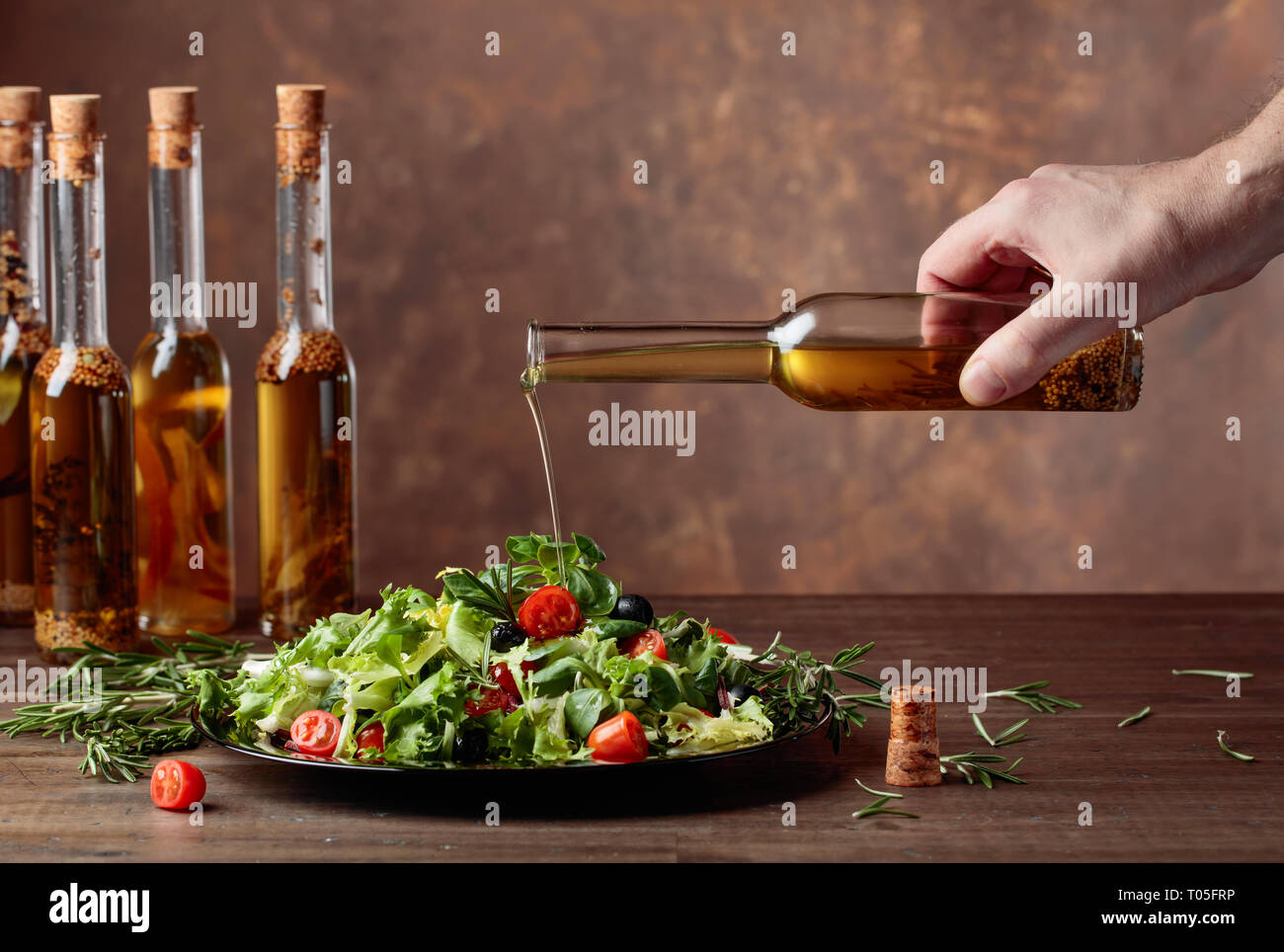 Salat mit Olivenöl Gießen von einer kleinen Flasche. Kopieren Sie Platz. Stockfoto
