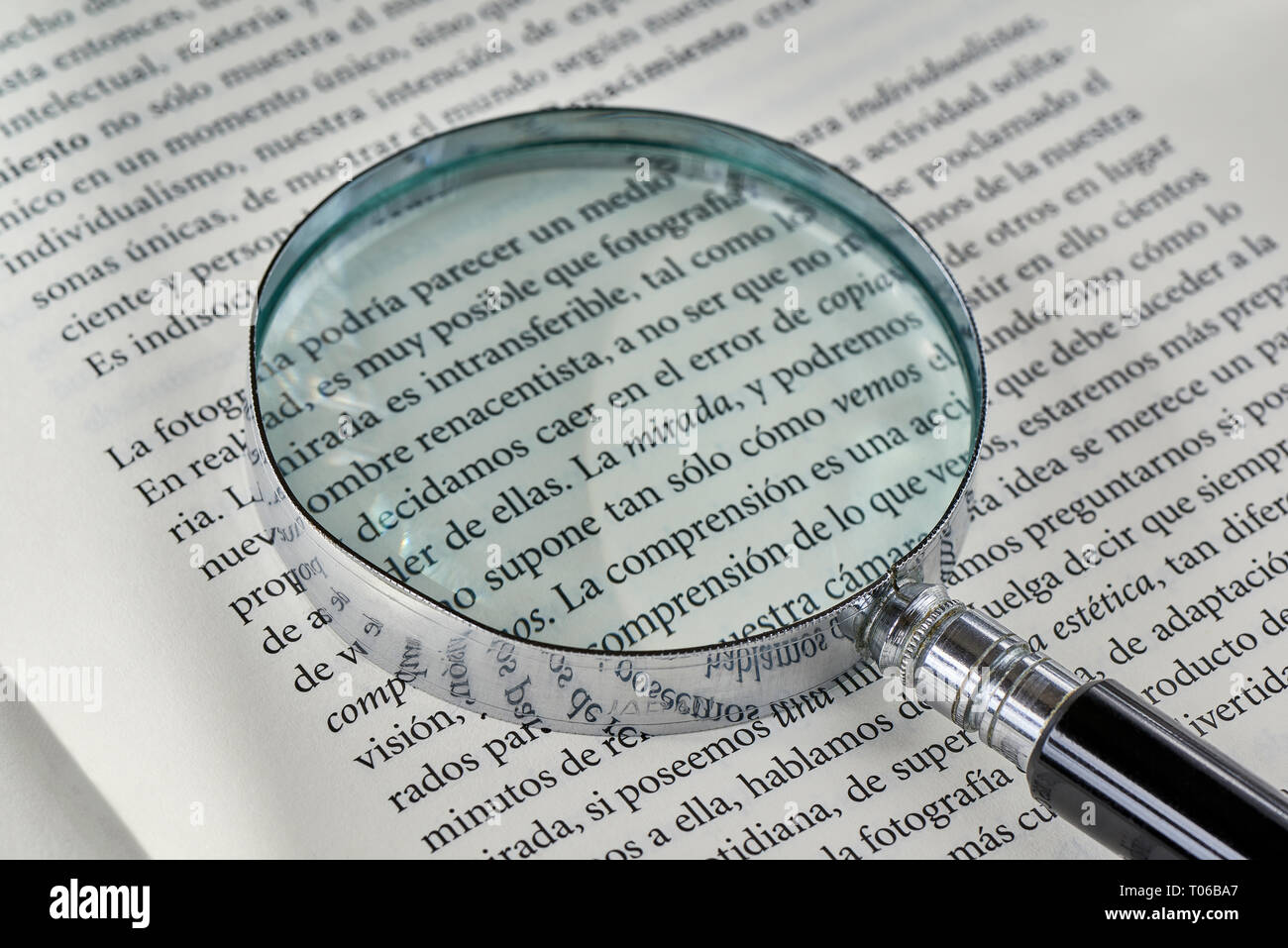 Das Wort suchen in Kursivschrift in einem Buch, durch ein Vergrößerungsglas betrachtet. Stockfoto