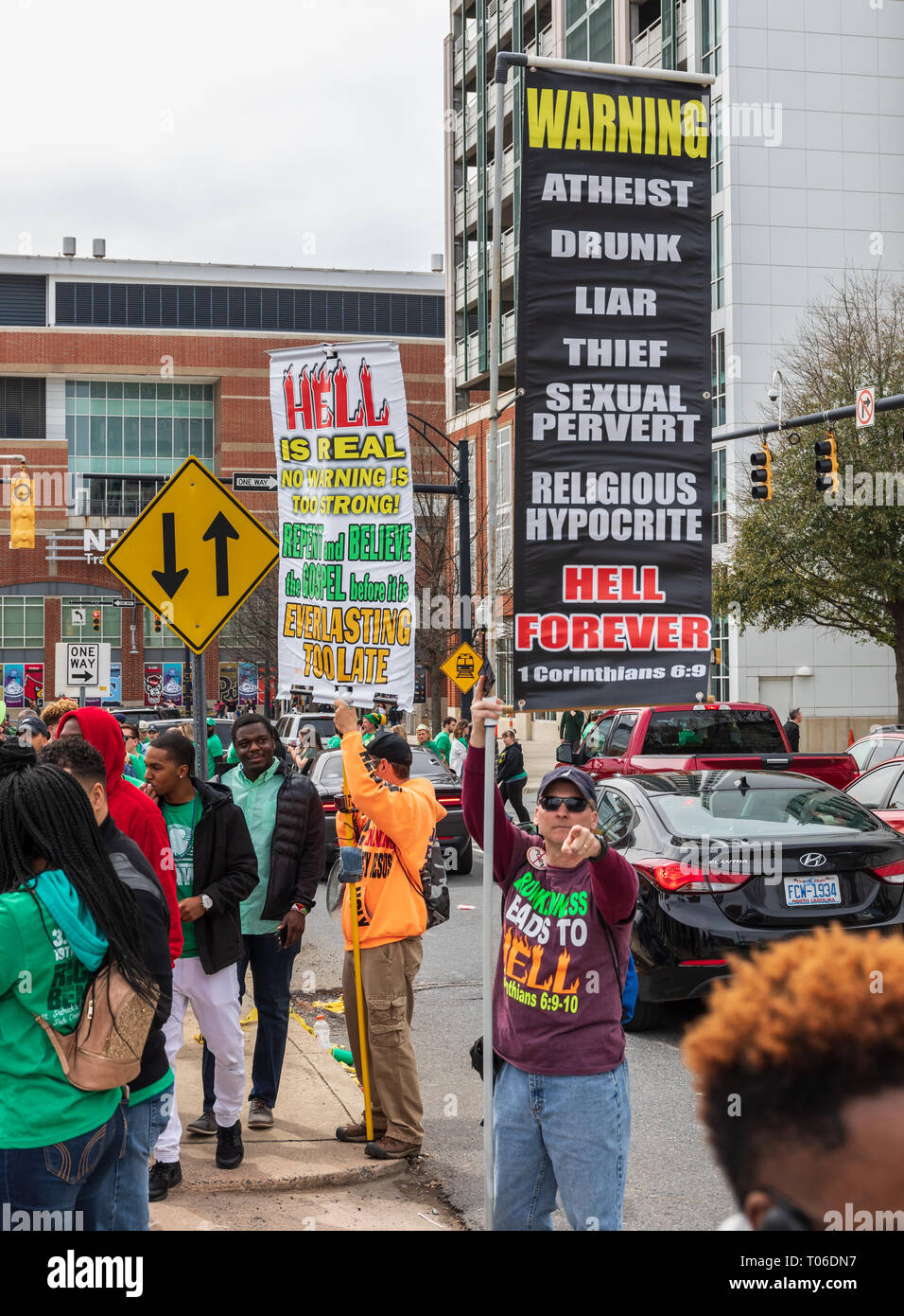CHARLOTTE, NC, USA -3/16/19: Ein Mann zeigt auf Kamera, während mit einem Schild, Liste von Verhaltensweisen, die 'Hölle auf ewig". Stockfoto