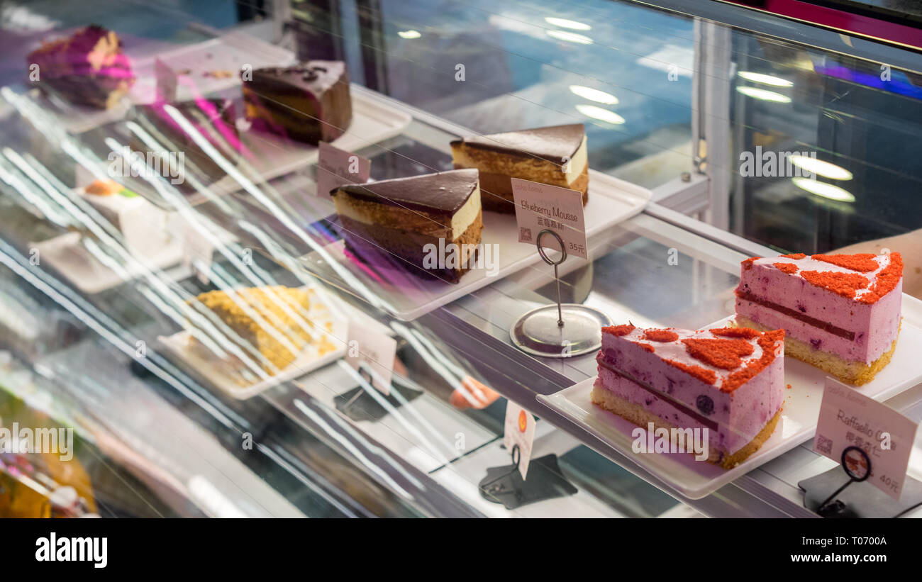 Ein Fenster in einer Bäckerei mit vielen Kuchen und Desserts, ein Spiegelbild von Lichtern, Schokolade, napoleon, samt Stockfoto