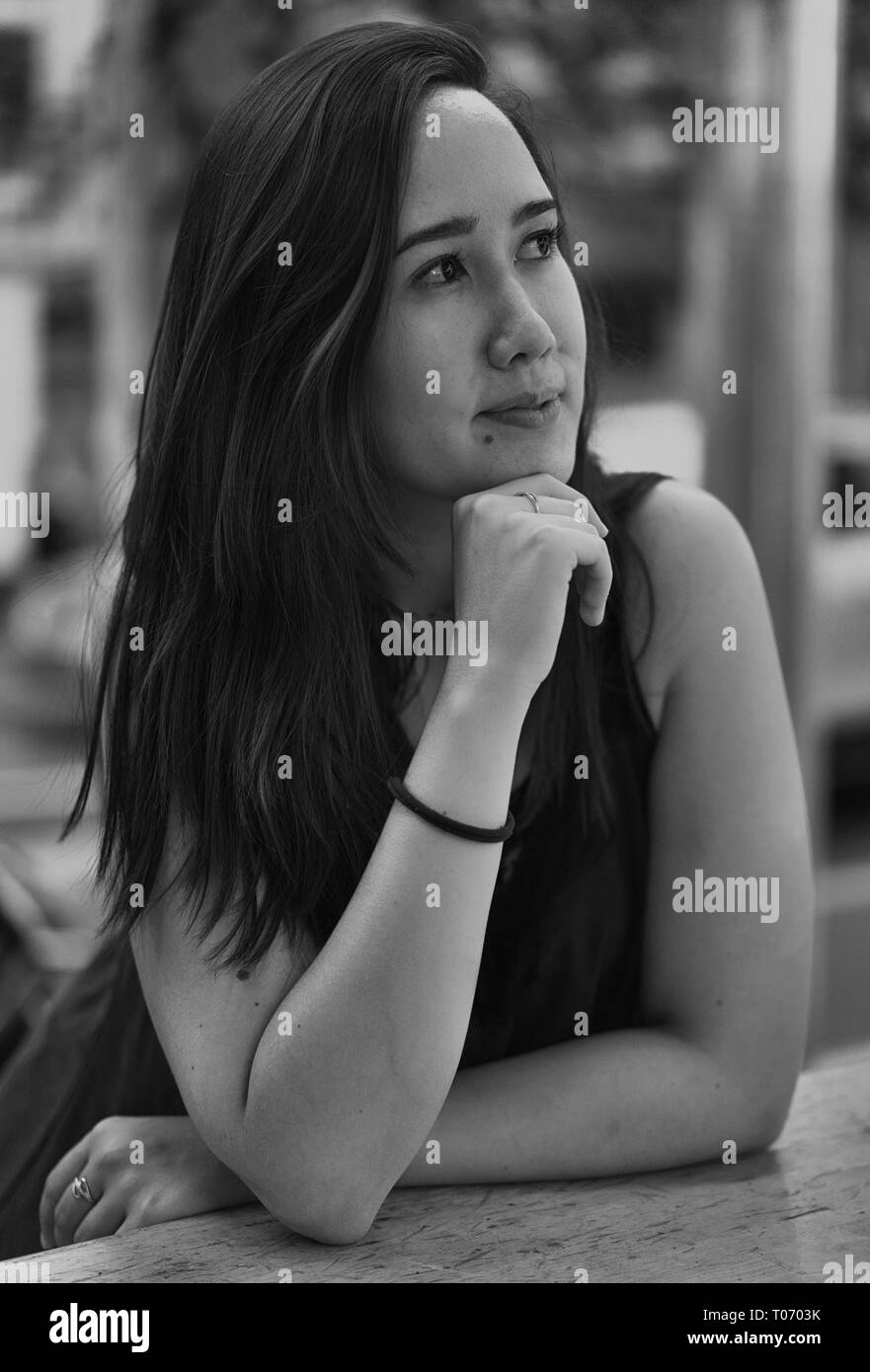 Ein wunderschönes Mädchen, das im Café sitzt und träumt, schwarz-weiß Stockfoto