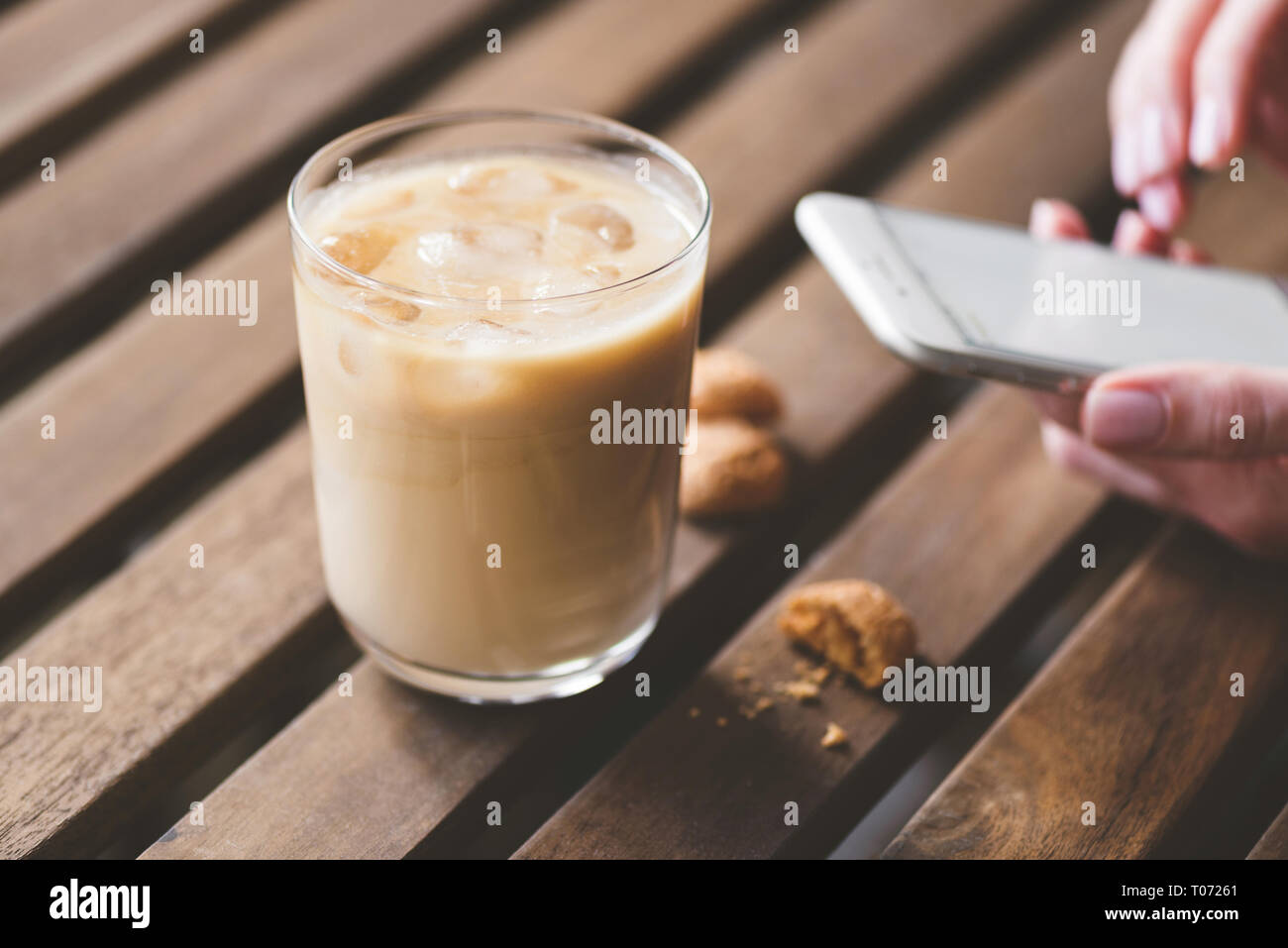 Ice latte, Cookies und Smartphone. Frühstück im Cafe. Morgendliche Routine Stockfoto