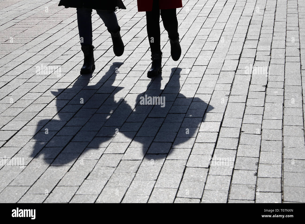 Silhouetten und Schatten der zwei Frauen auf der Straße. Menschen Hand in Hand im Freien, Konzept der Zwillinge, weibliche Freundschaft, Lesben, dramatische Stockfoto