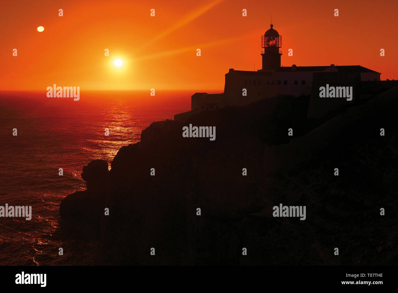 Romantischer Sonnenuntergang an der felsigen Küste mit Leuchtturm Stockfoto