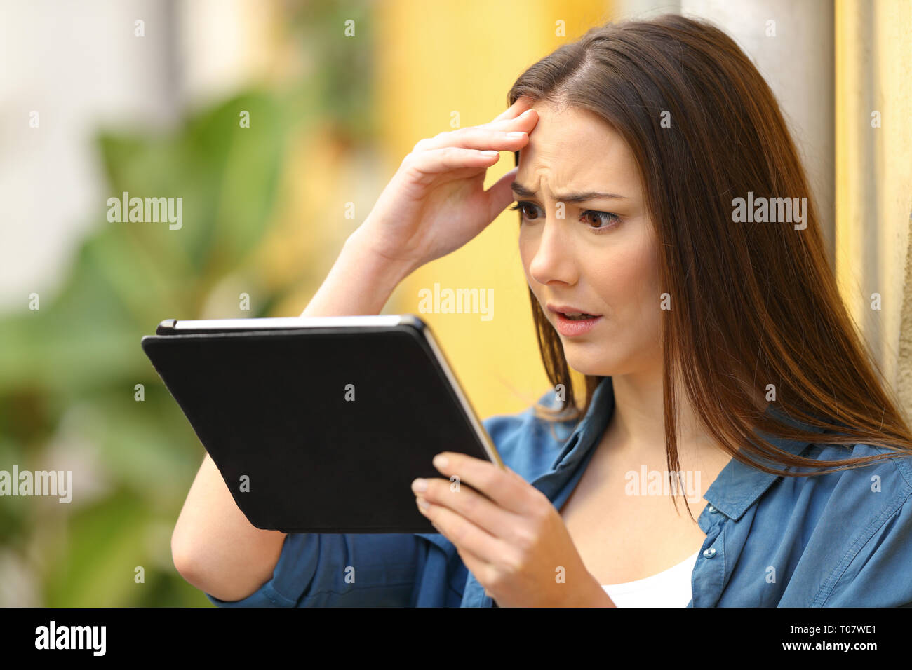 Besorgt Frau ist Kontrolle tablet online Inhalt eine bunte Straße Stockfoto