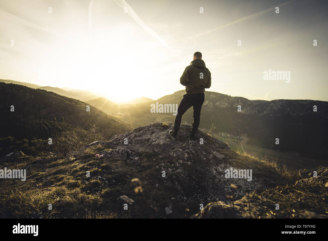 Man steht auf dem Gipfel eines Berges und Beobachten an Sun schönen Augenblick das Wunder der Natur. Stockfoto