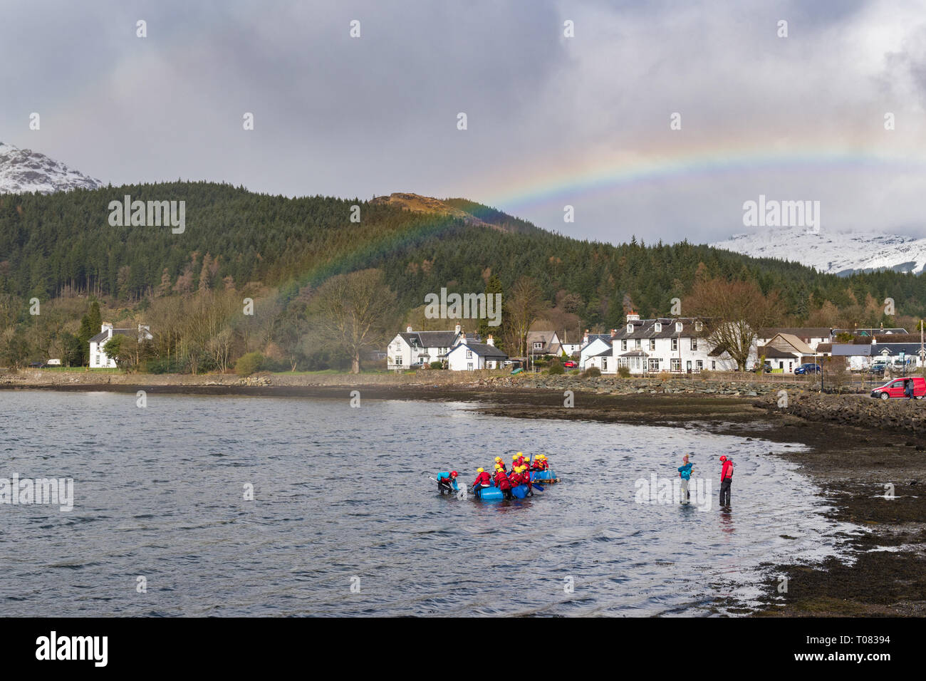 Glen Arbor, Argyll und Bute, Schottland - Jugendliche trotzen das kühle Wasser des Loch Goil unter einem Regenbogen beim Flossbau Aktivität Stockfoto