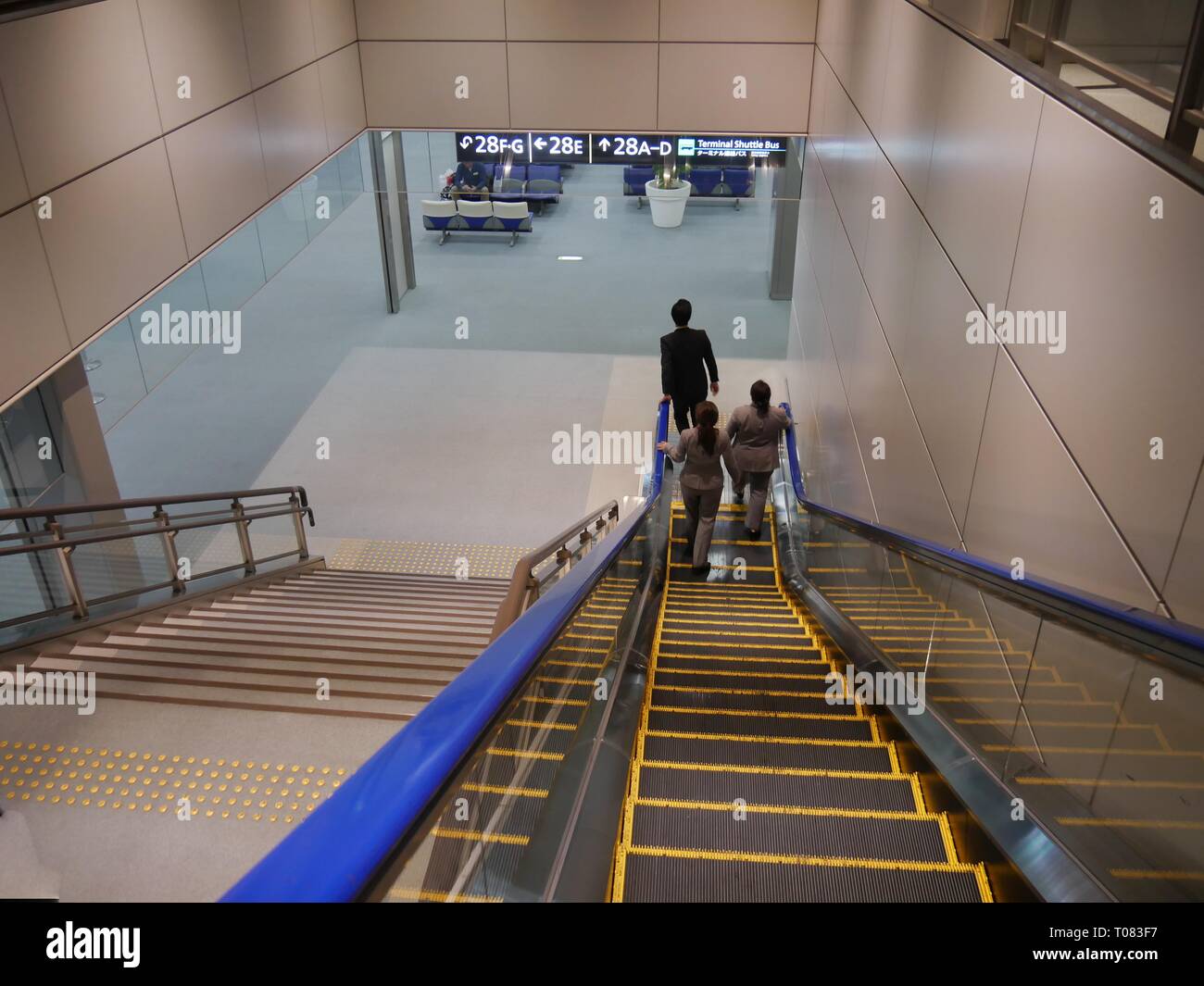 TOKIO, JAPAN – 2018. FEBRUAR: Die Flughafencrew geht die Rolltreppe hinunter zu den neuesten Abflugstoren am Narita International Airport. Stockfoto