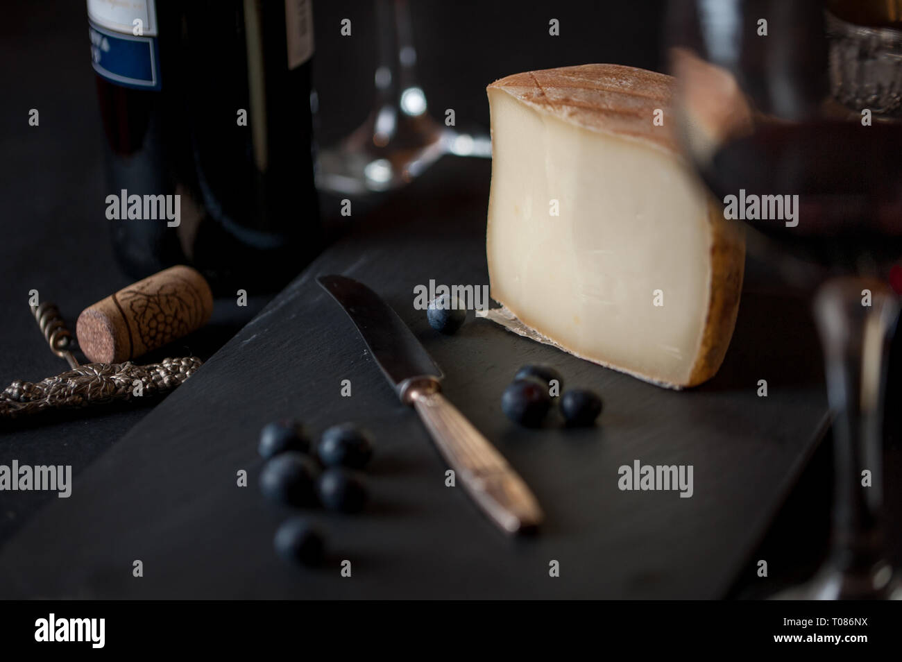 Käse Wein und Beeren mit antiken Messer, Korkenzieher, Gläser und eine Flasche Wein. Stockfoto