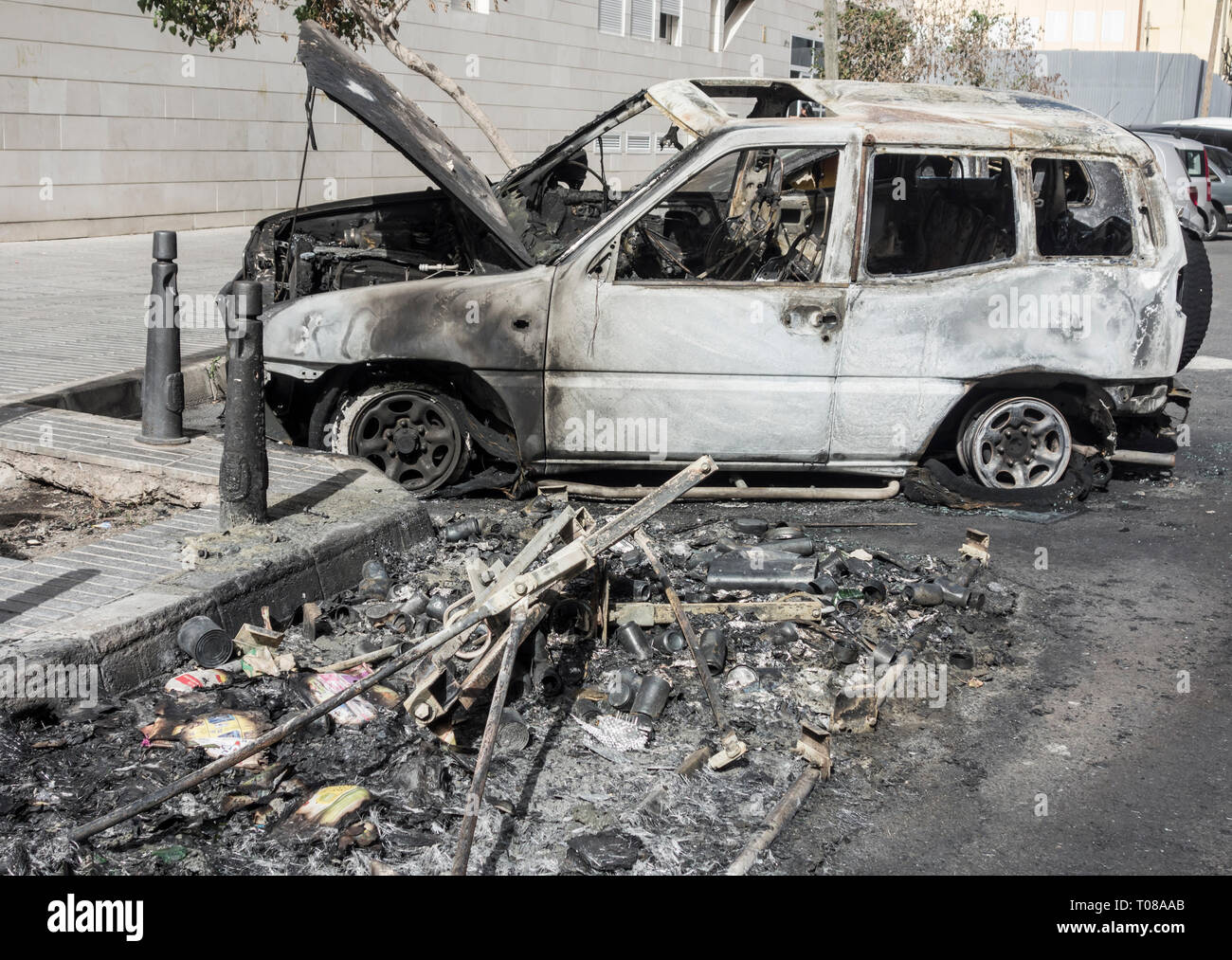 Ausgebrannte Autos, die neben Müll container angezündet durch Vandalen in der Straße geparkt waren in Spanien Stockfoto