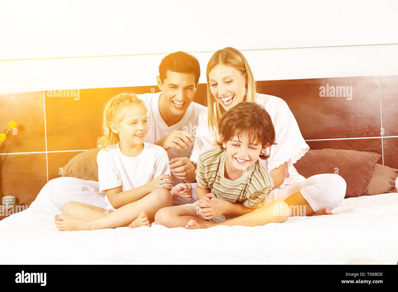Lachend Familie sitzt im Bett mit zwei Kindern und Kitzeln einander Stockfoto