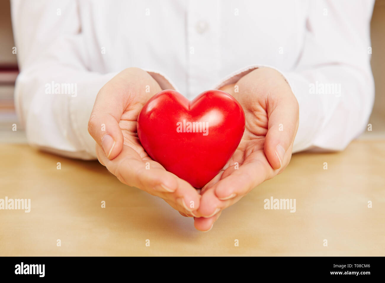 Frau hält ein kleines rotes Herz in der Hand als Symbol der Liebe Stockfoto