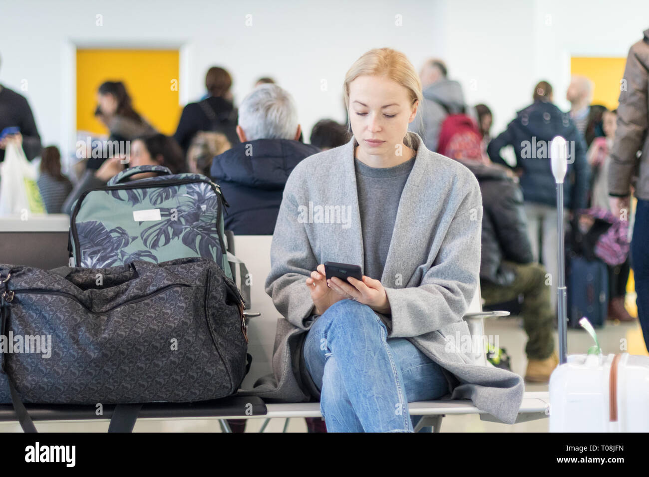 Weibliche Reisende können Sie über Ihr Handy während der Wartezeit in ein Flugzeug steigen bei der Abreise Gates am Flughafen. Stockfoto