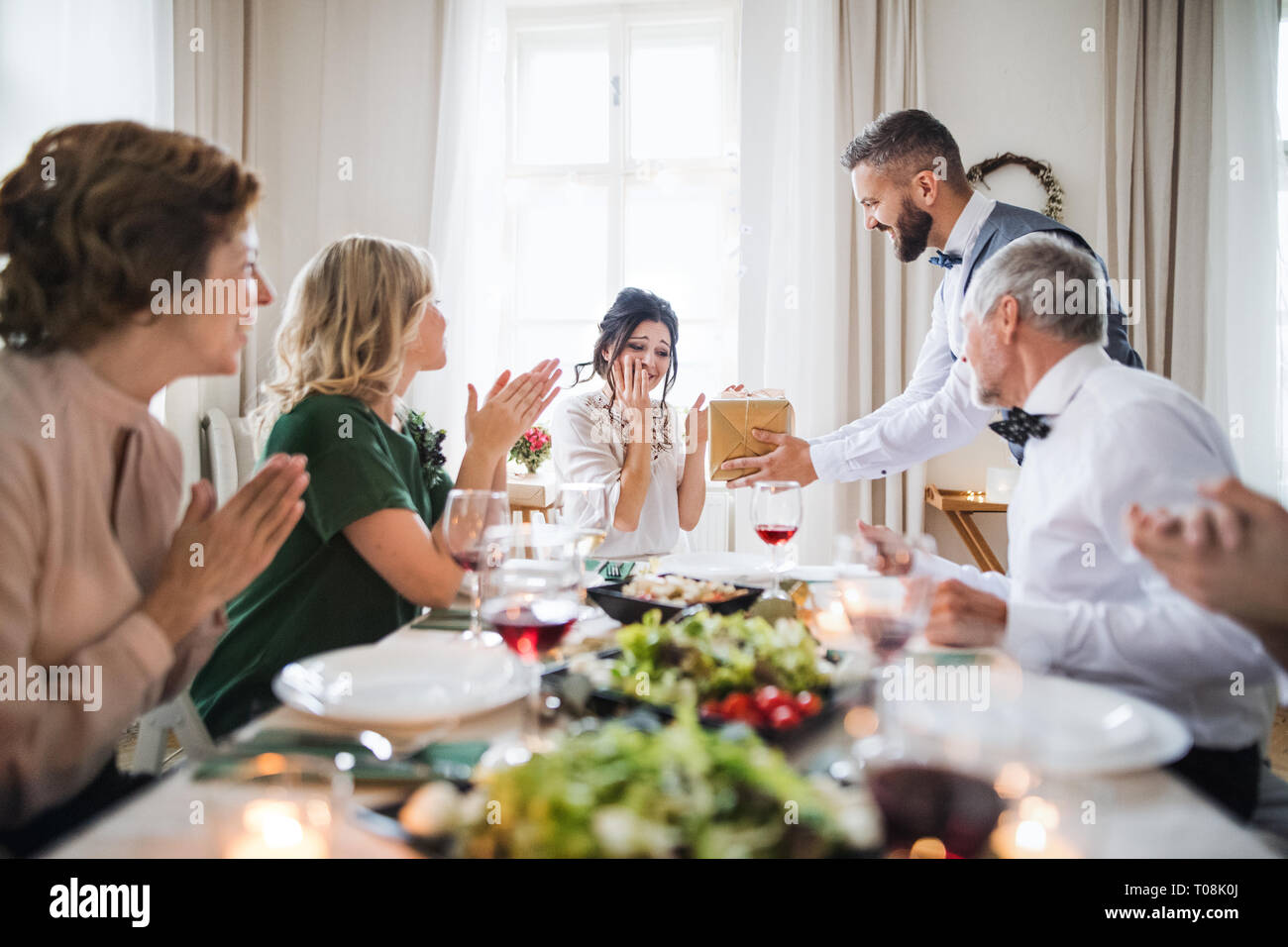 Ein Mann, der ein Geschenk überrascht junge Frau auf einer Geburtstagsfeier in der Familie. Stockfoto